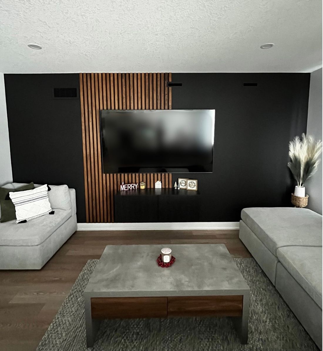 Living room with a black feature wall, wood slat panel and grey sofa, painted by Moonlight Painters in St. Thomas, Ontario.